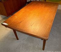Top view of the rectangular solid teak tabletop showing wood grain and small water mark at one end.