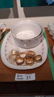 Top view showing 16-inch white china platter, one serving bowl, and 8 gold metal napkin rings.