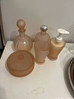 Photo showing entire 5-piece bath set on white countertop including two perfume bottles, lotion pump, tumbler and covered glass jar.