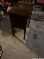 Side view of the wooden chest showing its smooth polished surface and tapered legs.