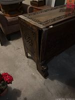 Partial top and side view showing carved top panel and carved side leg/foot of the chest