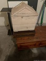 Large wooden chest with peaked roof lid and rope handle on top of two wooden boxes