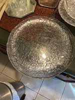 Large round glass platter with crackled textured surface reflecting light, view from above
