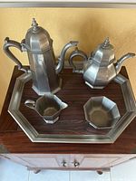 Overall view of the pewter tea and coffee set on wooden surface.
