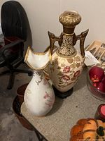 Pair of decorative vases on a table with surrounding items and chairs in background