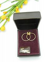 Pair of 14K gold sleeper hoop earrings displayed inside black box with burgundy velvet interior and Simpsons brand tag.