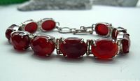 Close-up of faceted oval carnelian stones set in sterling silver with hinged joints.