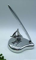 Front angle of the chrome pen holder with sailboat and attached silver pen