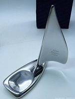 Polished metal sailboat sculpture with original blue box behind it.