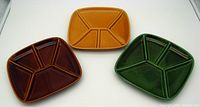 Top view of three vintage fondue plates showing five divided compartments in brown, mustard yellow, and green retro colors.