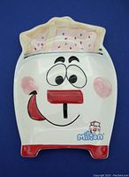 Front view of the ceramic dish shaped like a cheerful toaster with two frosted Pop Tarts in the slot and cartoon face.