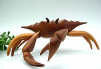 Side angle showing the wooden crab figure with articulated legs and claws, natural brown teak wood tones visible