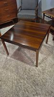 Full view of square rosewood coffee table showing top grain and legs