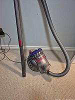 Dyson canister vacuum with hose and wand standing upright