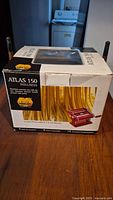 Closed box showing Atlas 150 Wellness branding and red pasta machine image