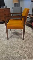 Side view of burnt orange upholstered armchair showing wood frame and legs