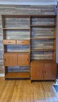 Full frontal view of assembled two-bay teak wall unit with shelves, drawers and cabinets