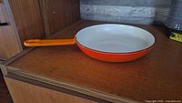 Side view of skillet showing orange exterior and handle