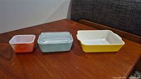 three colored glass refrigerator dishes with lid on turquoise dish
