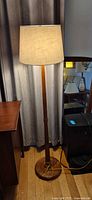 Full view of the illuminated wood floor lamp with shade