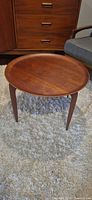 Assembled round teak tray table on rug