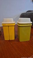 Front view of both yellow and green containers with white lids attached