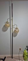 Full view of tension pole lamp, two amber glass globes, dark brown pole