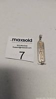Photo showing sterling silver pendant with gold-tone Egyptian hieroglyphs vertically aligned in center on white background with MaxSold inventory tag