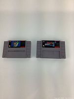 Two vintage SNES game cartridges displayed side by side, showing front labels of Super Mario Kart and Dracula X, both grey plastic with red and black label sections.