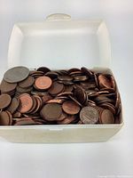 Top view of the plastic container showing the variety of copper pennies and a few silver coins inside