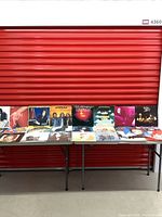 25 vintage classic rock record vinyl albums displayed standing and laid out on folding tables in a red storage unit environment.