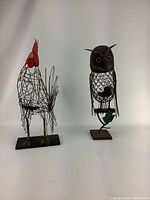 Front view of both metal lawn ornaments: rooster on left, owl on right, showing full figures and bases.