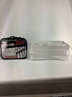 Photo of the sealed 30-piece bungee cord set in a black carrying case beside the wrapped white plastic storage shelf