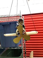 Front view of painted metal propeller plane with seated pilot figurine suspended by cord