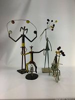 Four vintage hand made metal sculptures depicting circus themes: a tall performer with a ring and colored spheres, a unicyclist with hoop, a balloon holder, and animals pulling a balloon cart.