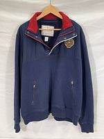 Front view of navy blue Eddie Bauer pullover jacket with red collar, partial snap-button placket, zipper pockets, and logo patch on chest.