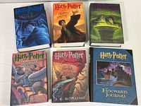 Six books arranged with front covers visible, featuring five Harry Potter titles and one Hogwarts Journal.