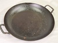 Top view of the iron paella pan showing the seasoned cooking surface and handles