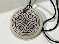 Close-up of the porcelain pendant front showing detailed Celtic cross design in black on white background.