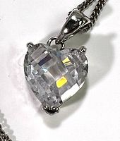 Close-up of heart-shaped crystal pendant set in a silver prong setting attached to the chain.