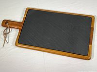 Overall view of wooden board with removable black slate insert on top, showing rectangular shape with handle and leather loop