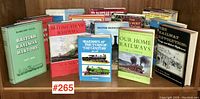 Front view of 13 books on British trains and railways arranged horizontally on a wooden shelf, titles visible.