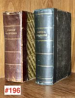 Two books standing upright showing binding and covers: London Gazetteer 1833 in marbled half leather and Natural Philosophy 1873 in black half leather with gilt titles.