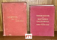 Two cloth-bound antique travel guides displayed side by side standing upright, showing red cloth covers with gilt titles: 'Boston and Its Suburbs' and 'Traveler's Hand Book to Southern California'