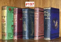 Front view of the five antique decorative Victorian bound books, showing each unique cloth cover design in green, maroon, blue, and purple with gilt embossing.