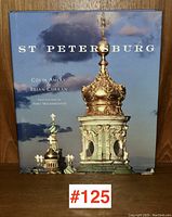 Front cover of hardcover art book 'St Petersburg' showing the gilded dome of a church with cloudy sky background.