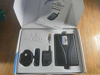 Box opened showing control module, remote fob, antenna/siren unit, battery and manual