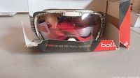 Front view of goggles in damaged box showing mirrored lens and Bolle branding