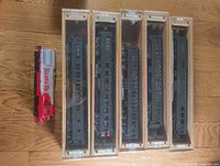 Five passenger cars in individual wooden display cases alongside Santa Fe diesel locomotive