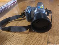 Front angled view of Sony DSC-H2 camera showing lens hood, grip, strap and body details